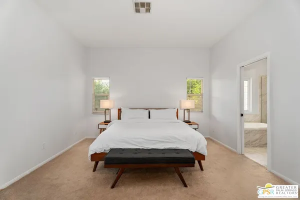 a bed sitting in a spacious bedroom next to a window