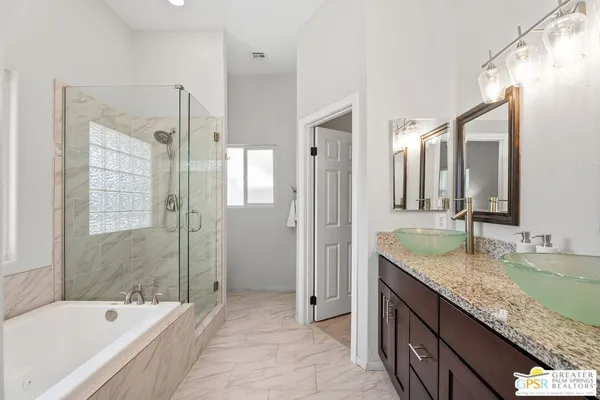 a bathroom with a granite countertop tub sink and mirror