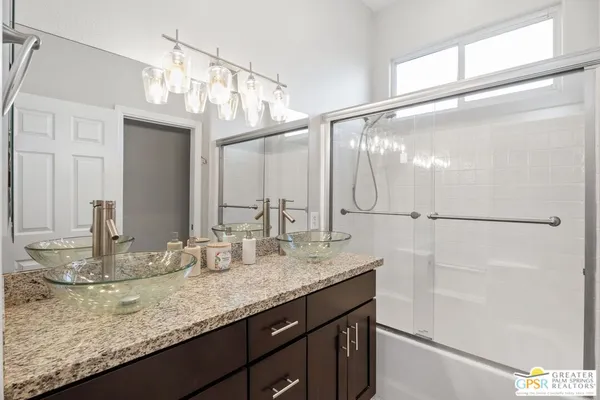 a bathroom with a granite countertop sink a mirror and a shower