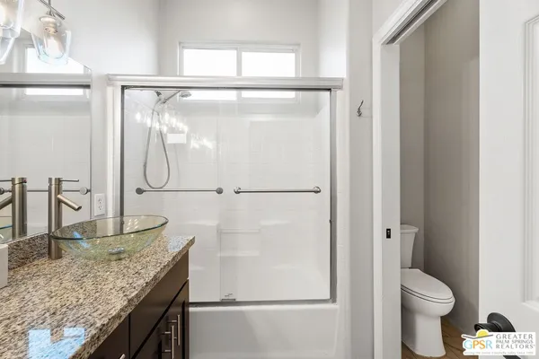 a bathroom with a granite countertop sink mirror vanity and toilet
