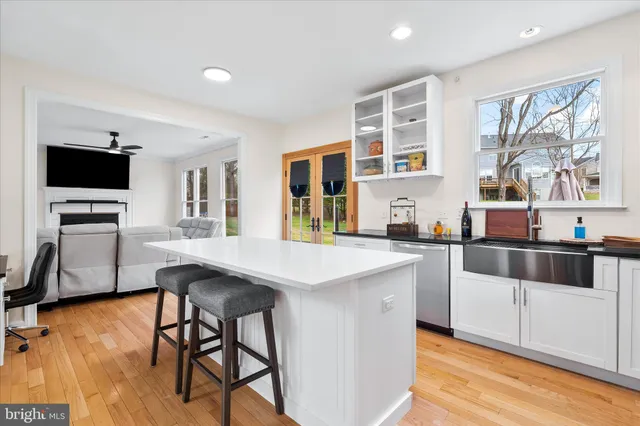 a kitchen with stainless steel appliances kitchen island granite countertop a stove top oven a sink a dining table and chairs with wooden floor