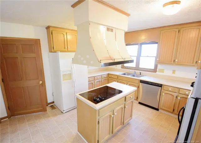 a kitchen that has a sink a stove top oven a refrigerator and a window