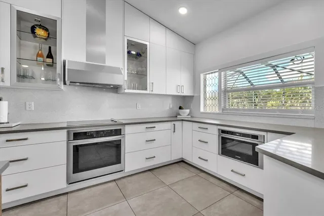 a kitchen with stainless steel appliances a dining table chairs and white cabinets