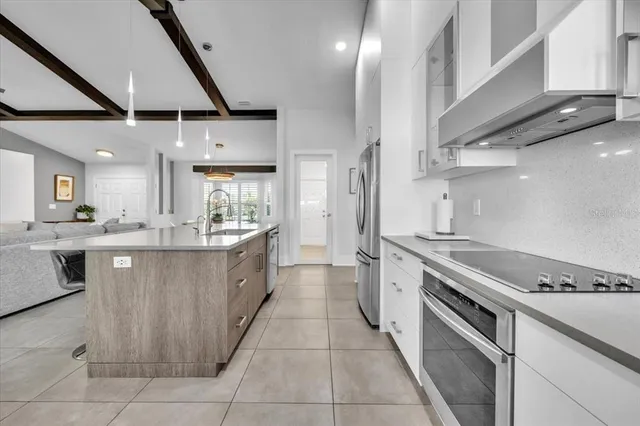 a kitchen with stainless steel appliances granite countertop a sink a stove a refrigerator cabinets and chairs