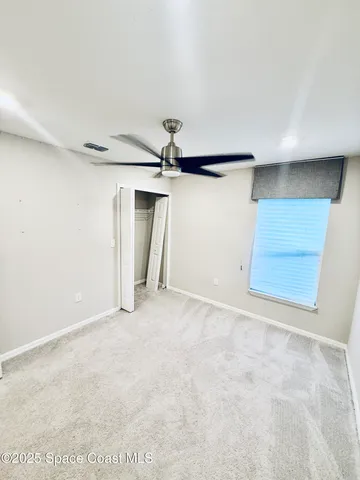 an empty room with a ceiling fan and window