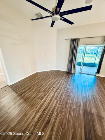 a view of empty room with wooden floor and fan