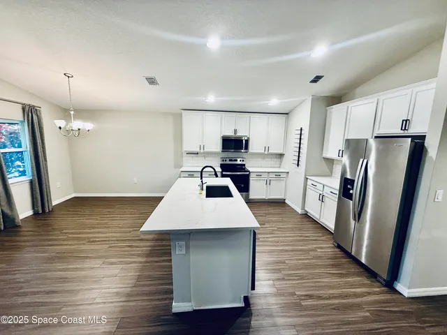 a kitchen with stainless steel appliances a refrigerator a stove a sink cabinets and wooden floor