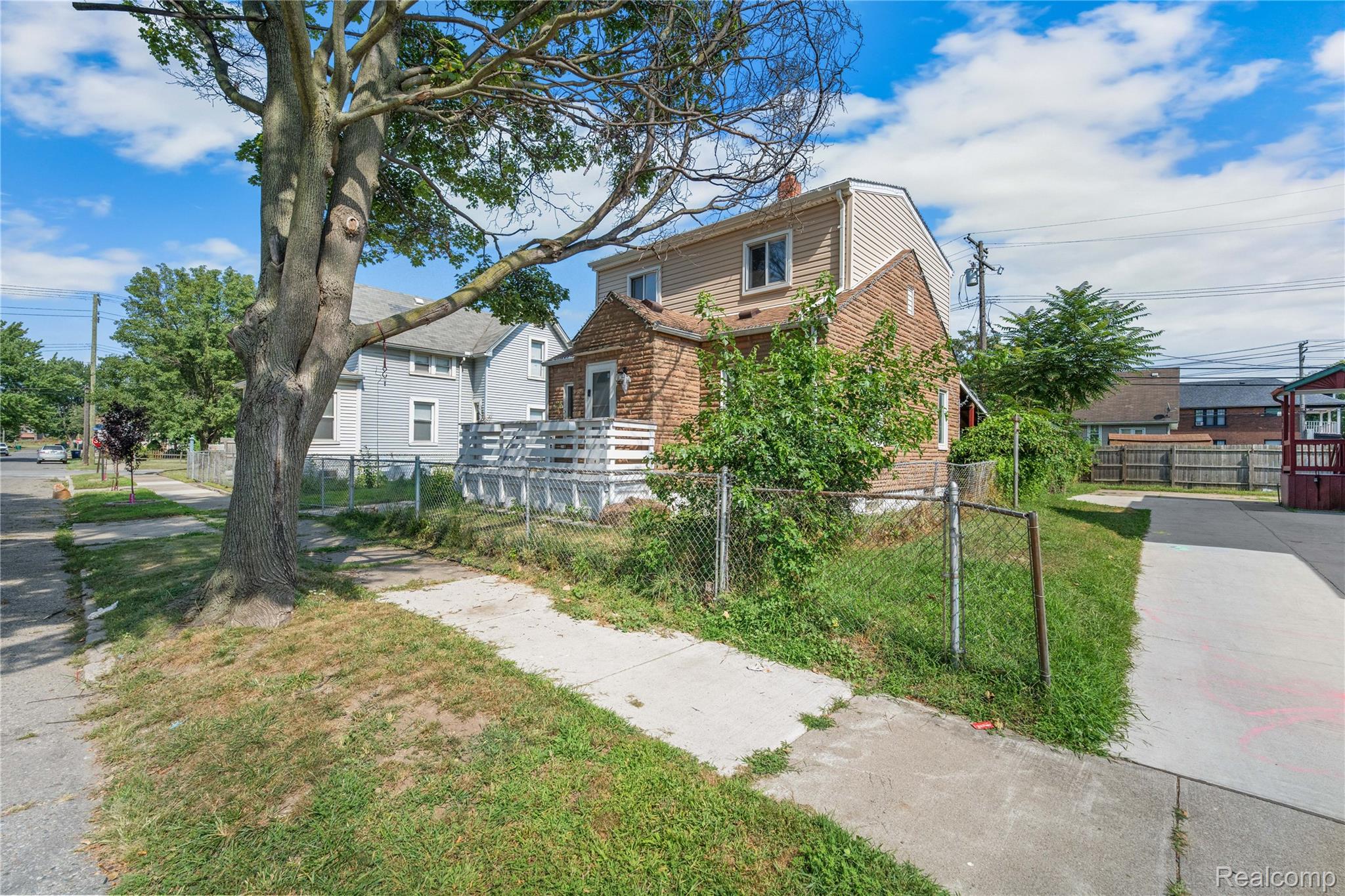 147 Charles Street River Rouge, MI 48218 - Photo 4 of 19 Two-story residence with brick and siding exterior, front porch with white railing, and chain-link fencing