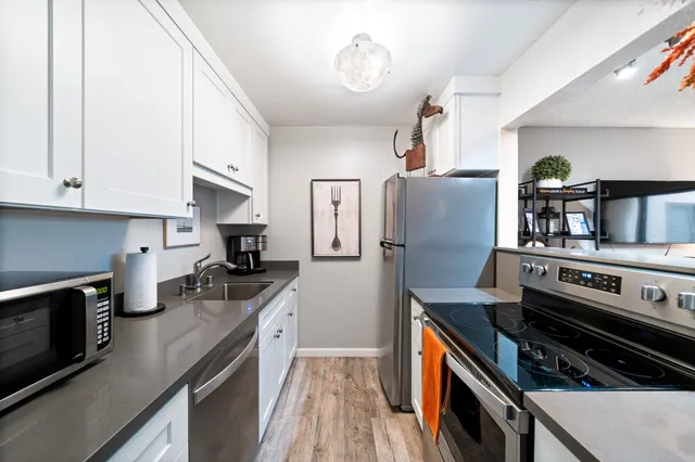 a kitchen with stainless steel appliances granite countertop a stove top oven a sink dishwasher and a refrigerator