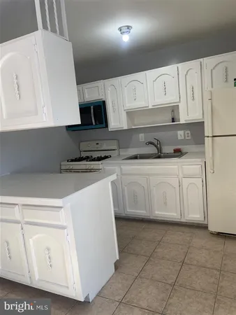 a kitchen with white cabinets sink and white appliances