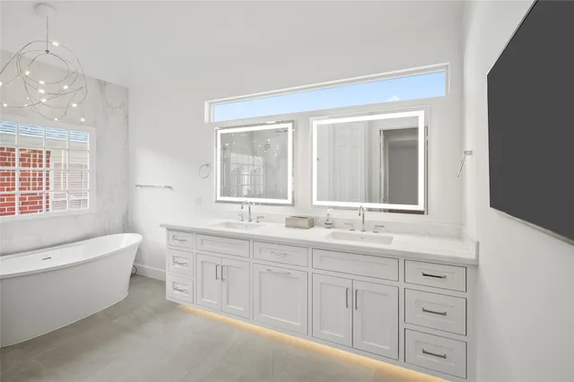 a bathroom with a double vanity sink a toilet a window and bathtub