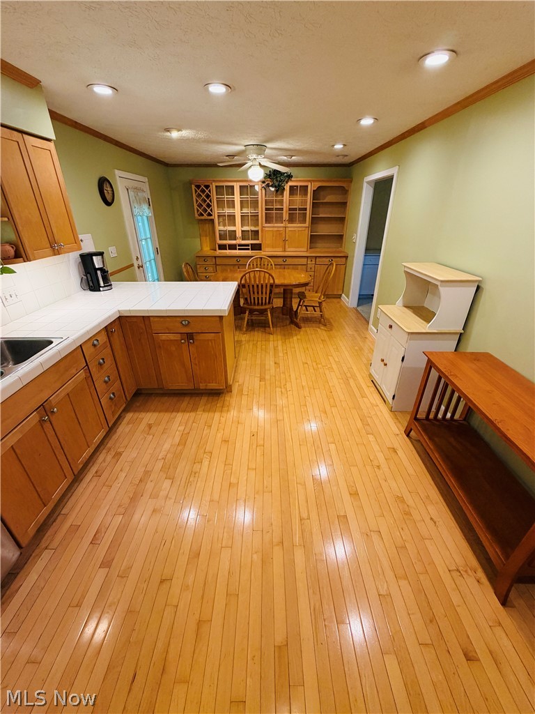 5770 Chapel Road Madison, OH 44057 - Photo 9 of 42 Hardwood flooring throughout, featuring recessed lighting, a ceiling fan, and built-in cabinetry with glass-front uppers