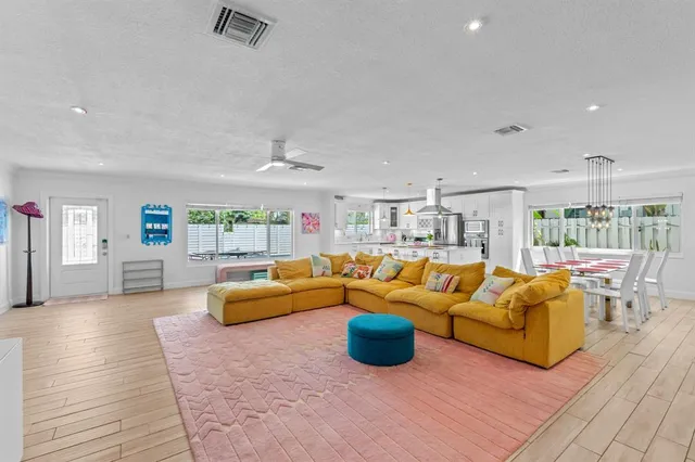 a kitchen with stainless steel appliances kitchen island granite countertop a dining table chairs and a refrigerator