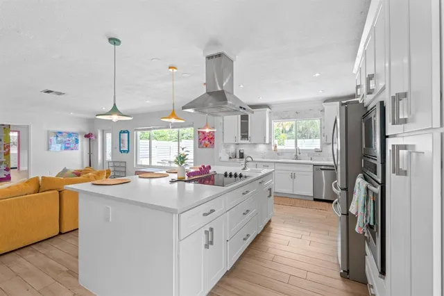 a kitchen that has a lot of white cabinets and stainless steel appliances