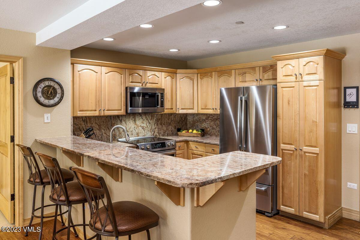 210 Offerson Road, Unit R225 Beaver Creek, CO 81620 - Photo 10 of 42 a kitchen with stainless steel appliances granite countertop a table chairs and a refrigerator