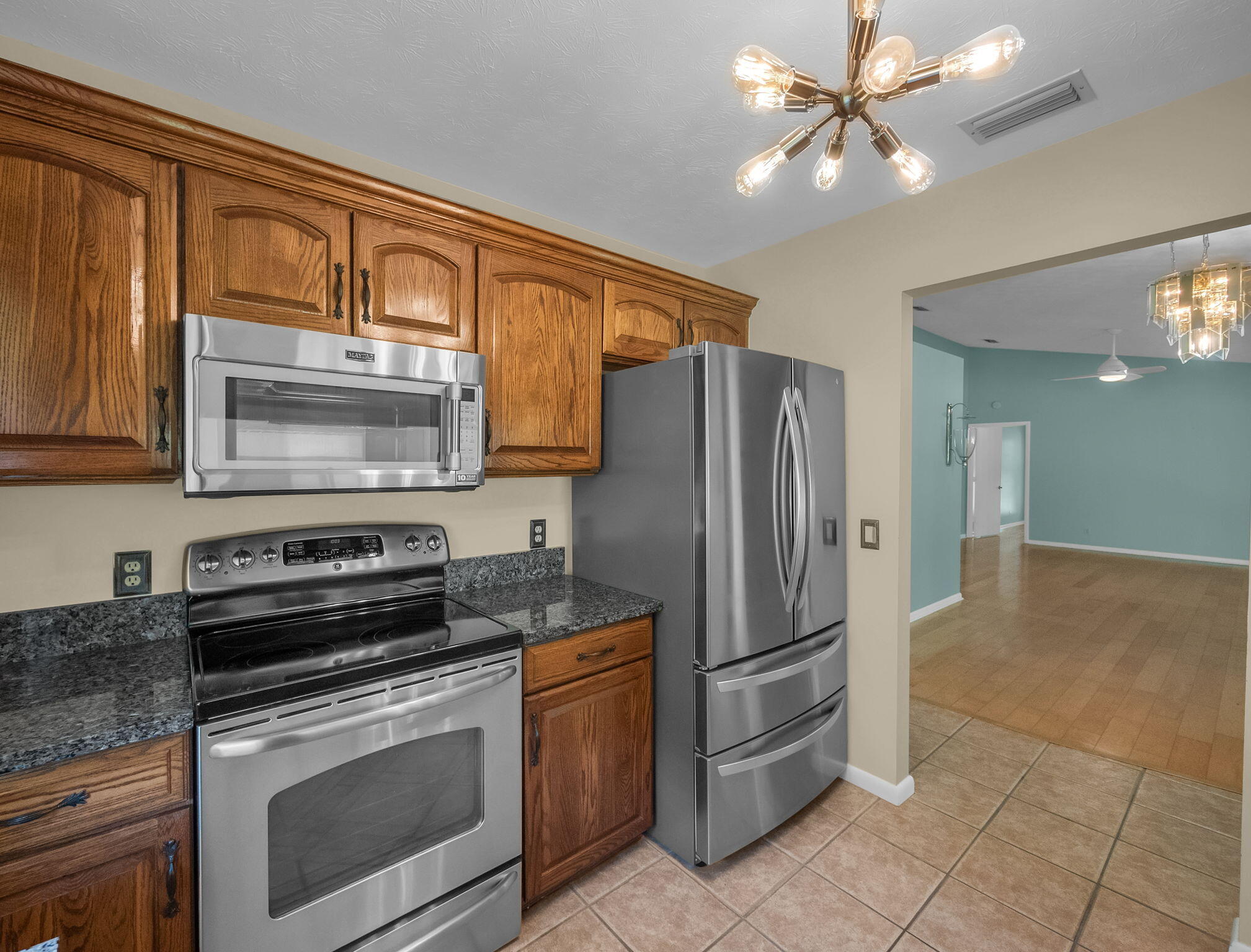 8165 Southeast Cypress Point Place Hobe Sound, FL 33455 - Photo 13 of 46 a kitchen with stainless steel appliances granite countertop a stove microwave and refrigerator