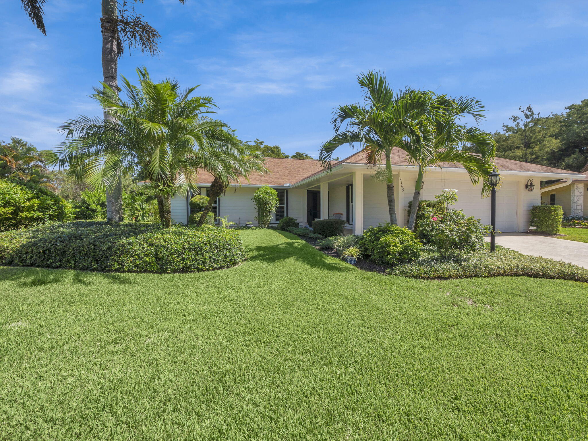 8165 Southeast Cypress Point Place Hobe Sound, FL 33455 - Photo 3 of 46 a front view of a house with a garden