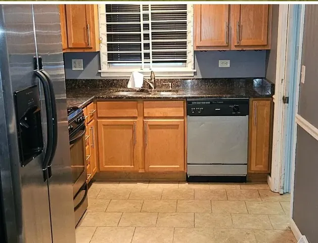 a kitchen with granite countertop a refrigerator and a sink
