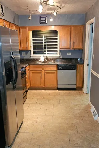 a kitchen with granite countertop a stove a sink and a refrigerator