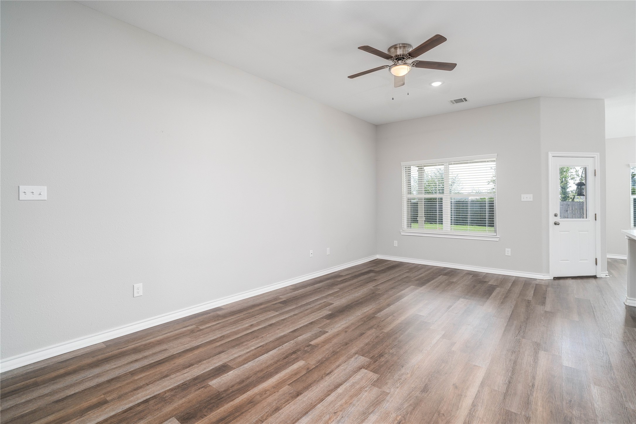 231 McCormick Street Columbus, TX 78934 - Photo 9 of 27 Living Room & Kitchen – Expansive main living space with ceiling fan, abundant natural light, and a clear view into the modern kitchen.