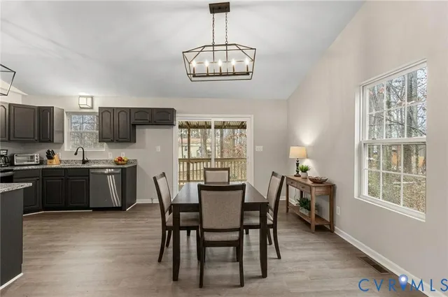 a kitchen with stainless steel appliances granite countertop a stove a refrigerator a kitchen island a dining table and chairs with wooden floor