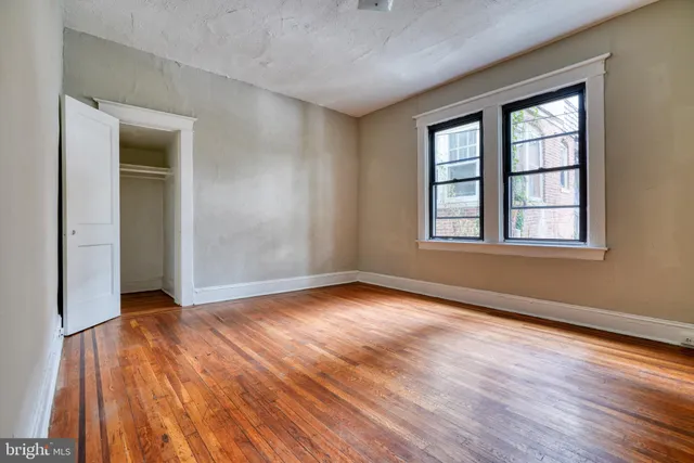 an empty room with wooden floor and windows