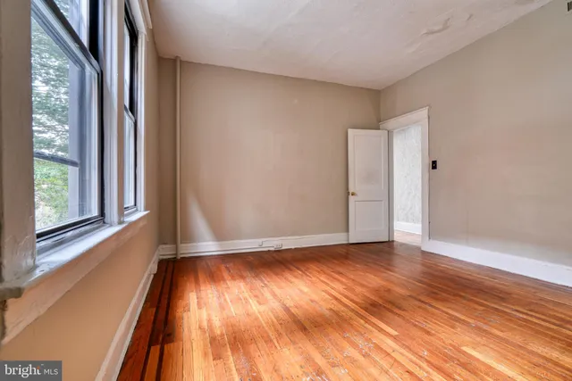 a view of an empty room with wooden floor and a window