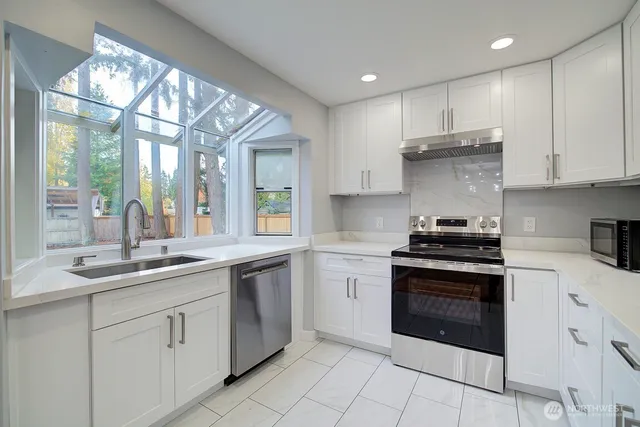 a kitchen with stainless steel appliances granite countertop a stove sink and cabinets