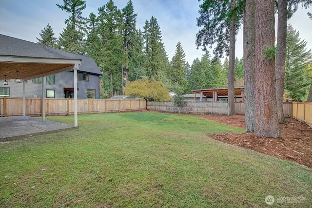 a view of a yard in front of a house with large windows
