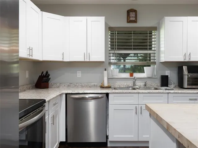 a kitchen with granite countertop a sink stainless steel appliances and cabinets