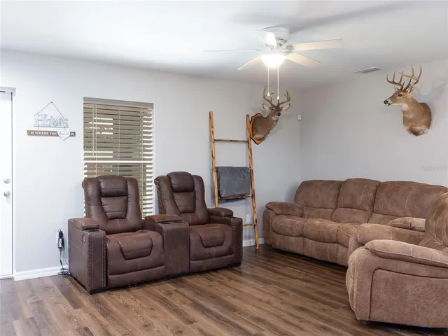 a living room with furniture a ceiling fan a lamp and a window