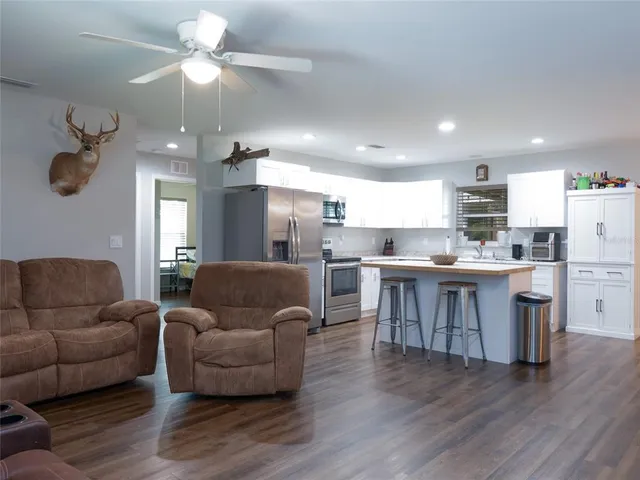 a living room with furniture kitchen and a wooden floor