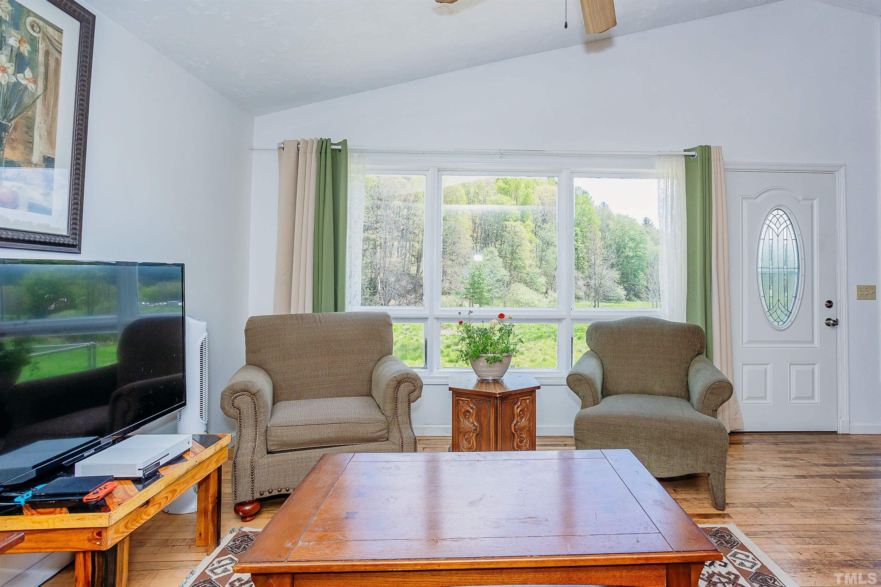 601 Fees Branch Road Lansing, NC 28643 - Photo 21 of 72 a living room with furniture a flat screen tv and a floor to ceiling window