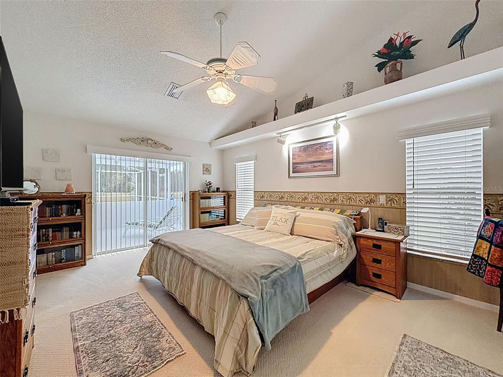 27380 Golf Course Loop Wesley Chapel, FL 33544 - Photo 14 of 27 a bedroom with a large bed a chandelier and dresser