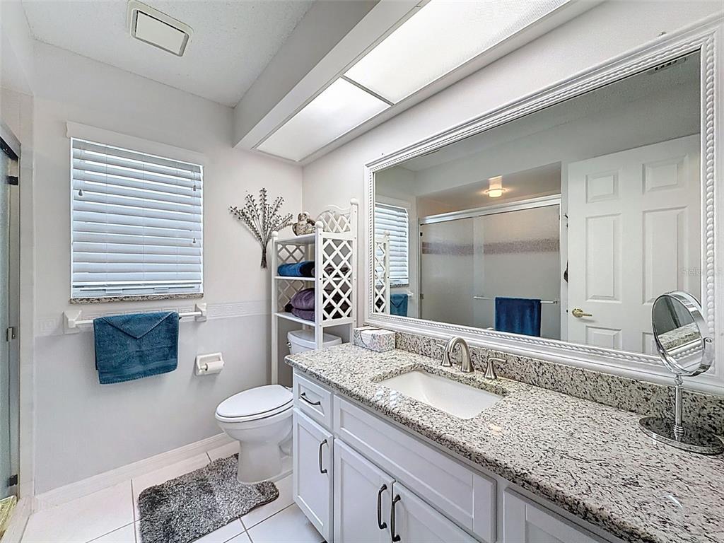 27380 Golf Course Loop Wesley Chapel, FL 33544 - Photo 18 of 27 a bathroom with a granite countertop sink a toilet a mirror and shower