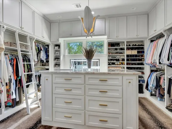 a view of walk in closet with clothes and shoes
