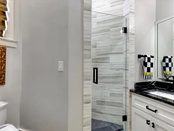 a bathroom with a granite countertop shower a toilet and a shower
