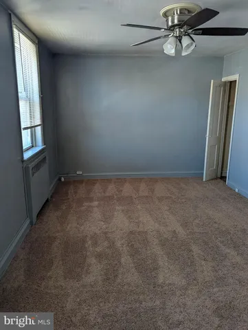 an empty room with windows and ceiling fan
