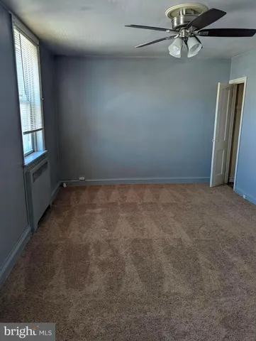 an empty room with windows and ceiling fan