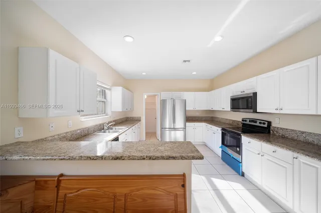 a kitchen with granite countertop a sink a stove top oven a counter space and cabinets