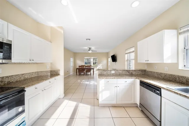 a large white kitchen with stainless steel appliances granite countertop a sink and cabinets