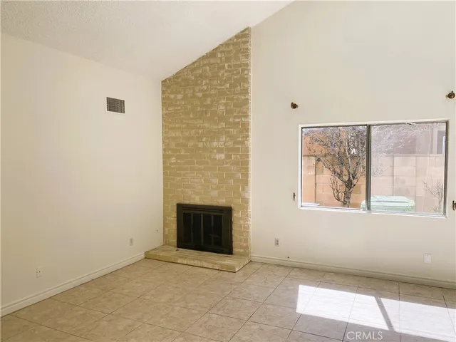 a view of an empty room with a fireplace and a window