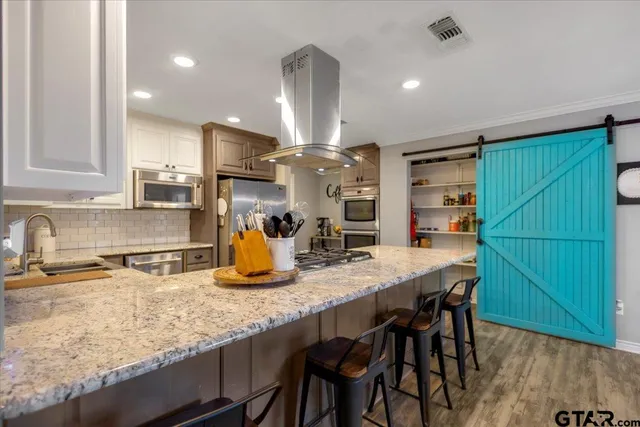 a kitchen with stainless steel appliances granite countertop a kitchen island a stove a sink a dining table and chairs