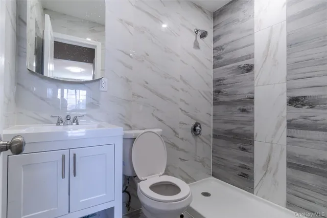 a bathroom with a granite countertop toilet a sink and mirror