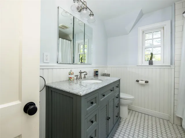 a bathroom with a granite countertop sink a toilet and a mirror