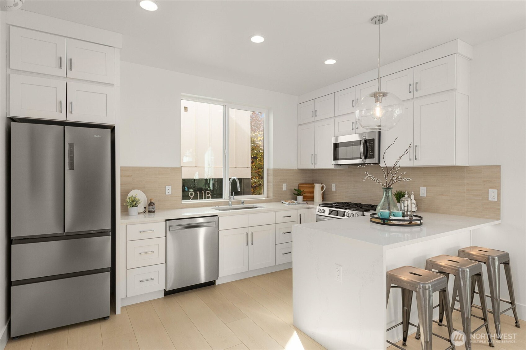 911 North 98th Street, Unit A Seattle, WA 98103 - Photo 11 of 26 a kitchen with stainless steel appliances a refrigerator sink and microwave