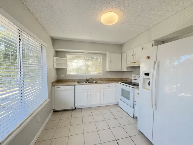 a kitchen with white cabinets a sink a window and stainless steel appliances