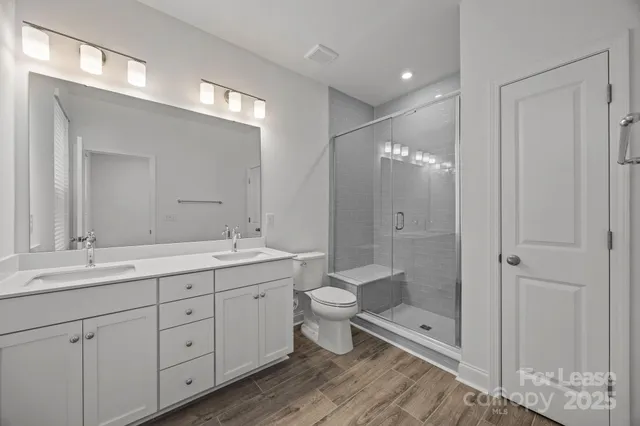 a bathroom with a double vanity sink toilet and shower