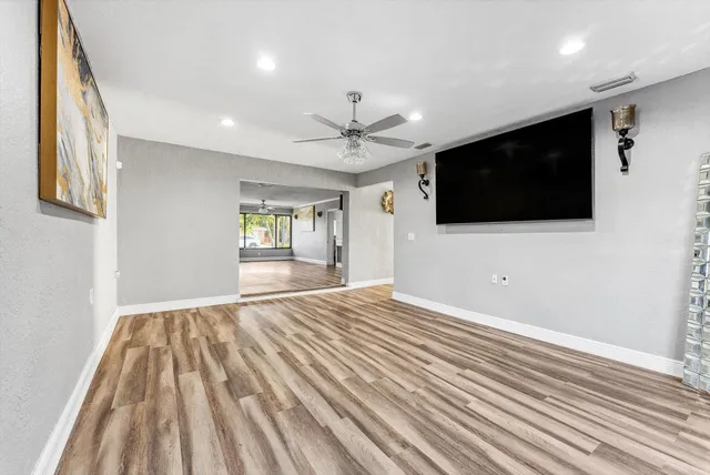 a view of a livingroom with a flat screen tv wooden floor and a ceiling fan