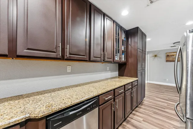a kitchen with granite countertop stainless steel appliances a sink stove and cabinets